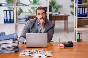 Young male sick employee suffering at workplace