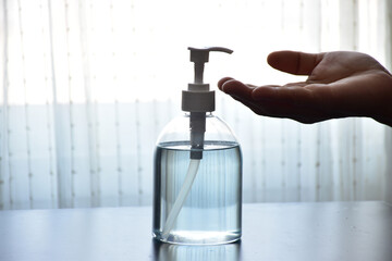 Hands pressing on a sanitizer gel bottle to prevent covid-19