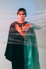 Female rights. Defocused art portrait. Social pressure. Insecure tired woman in black in red neon...