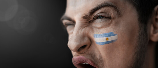 A screaming man with the image of the Argentina national flag on his face