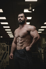 Fototapeta na wymiar strong young bearded caucasian man with perfect sport physique body in dark fitness athletic gym