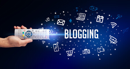 hand holding wireless peripheral with BLOGGING inscription, social media concept