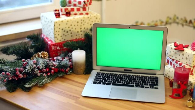 Blank green screen notebook with Christmas decoration. Presents for family. Chroma key laptop. Free content. Mockup monitor. Online greeting. Internet surfing. New Year Celebrating concept.
