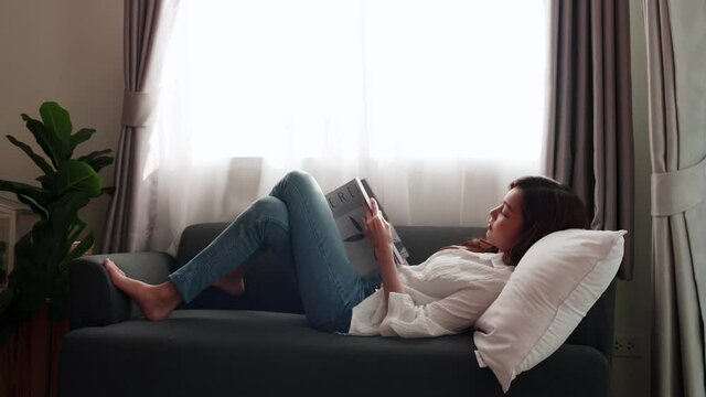 Asian women lie on the sofa, read magazines in their spare time, and relax in the mornings in the living room in the house.