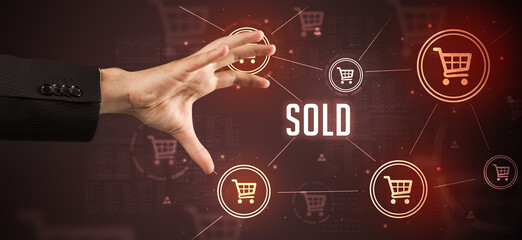 Close-Up of cropped hand pointing at SOLD inscription, online shopping concept