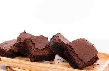 Pieces of fresh chocolate brownie on wooden plate on white background. Stack of fudgy chocolate...