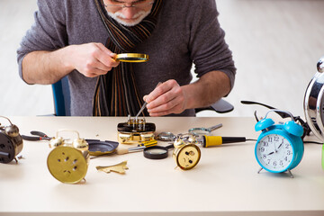 Old male watchmaker working in the workshop