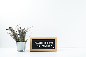 The inscription valentine's day in a frame of dry flowers in a transparent vase on a white background. Copy space, mock up.