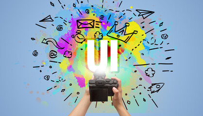 Close-up of a hand holding digital camera with abstract drawing and UI inscription