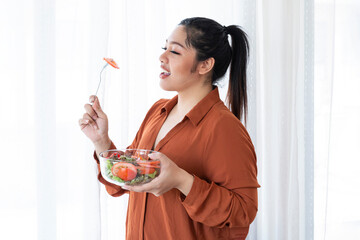 Overweight Woman Eating Bowl Of Fresh Vegetables. Obesity young women eat green organic vegetables....