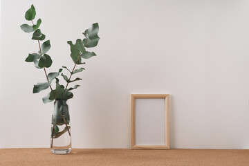 Frame and vase with eucalyptus on a white background. Mock up, copy space. Folk.