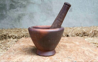 Mortar and pestle set on plywood behind cement wall.