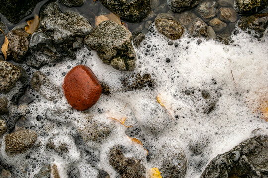 Pebbles at the bottom of the river in foam from the current.