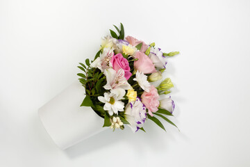 flat lay diagonal bouquet of roses, daisies, lisianthus, chrysanthemums, unopened buds in white paper box on a white background.