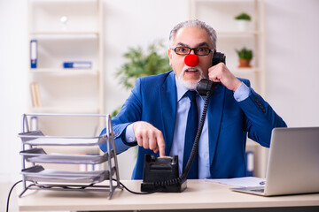 Old businessman clown working in the office