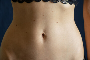 navel and belly of a young girl closeup on a dark background