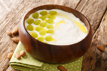 Spanish cold soup made from chopped almonds, bread and garlic served with green grapes close-up in a bowl on the table. horizontal