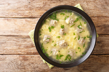Sciusceddu is a traditional Sicilian dish, made with small meatballs simmered in broth, topped with a mixture of eggs, ricotta, and caciocavallo closeup in the plate on the table. horizontal top view 