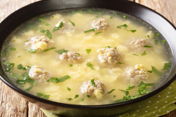 Sciusceddu or Italian Meatball and Egg Soup, is a popular, beef broth based soup served traditionally during Easter celebrations closeup in the plate on the table. horizontal