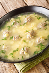 Sciusceddu is a soup in Italian cuisine prepared using meatballs and broken eggs as primary ingredients, served as a traditional Easter dish closeup in the plate on the table. vertical