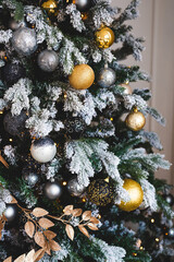 black, silver and gold Christmas tree decorations on the branches. Designer work