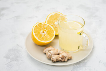 Cup of ginger and lemon lemonade with ingredients in plate