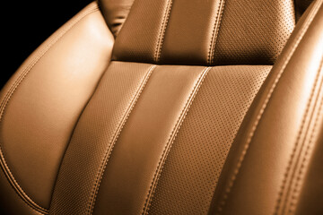 Modern luxury car brown leather interior. Part of orange perforated leather car seat details with white stitching. Interior of prestige car. Comfortable perforated leather seats. Perforated leather.