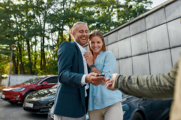Fototapeta na wymiar Cheerful young caucasian spouses receiving car key