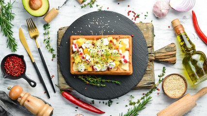 Breakfast. Belgian waffles with brie cheese, feta and parmesan. On a black stone plate.