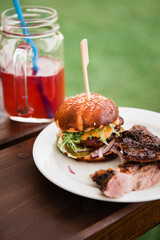 Hamburger with grilled meat and drink at outdoor party