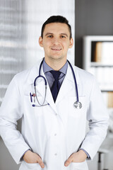 Male doctor standing straight in clinic near his working place. Perfect medical service in hospital. Medicine and healthcare concept