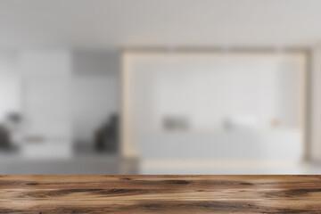 Wooden desk on foreground, blurred background of white reception room