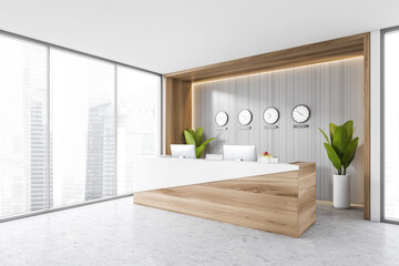 White reception room desk with computers and clocks on the wall near window