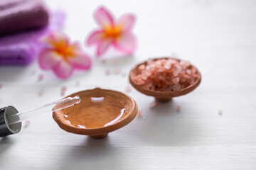 Oil massage in clay pot cup and blur image of himalayan salt and plumeria flowers for aromatherapy spa luxurious hotel.