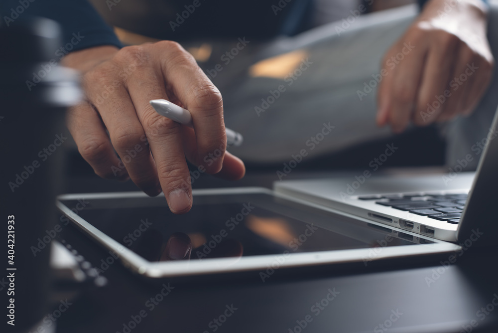 Poster close up of casual man hand using digital tablet during working on laptop computer at home