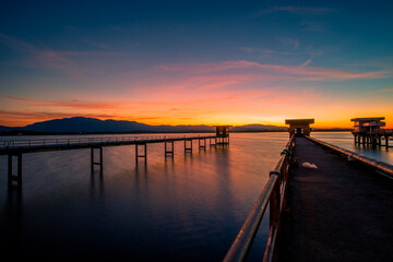 Obraz premium The background of the bridge stretches into the sea, with twilight light in the morning, beautiful colors, sky wallpaper and refreshing surroundings.