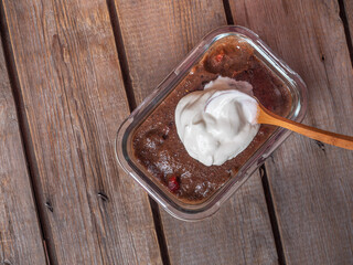 Bread soup with whipped cream in a glass container with a wooden spoon