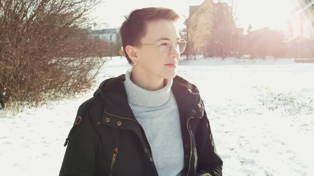 Short-haired elegant hipster tomboy girl with a vintage camera is taking a photo while smiling in Winter landscape slow-motion