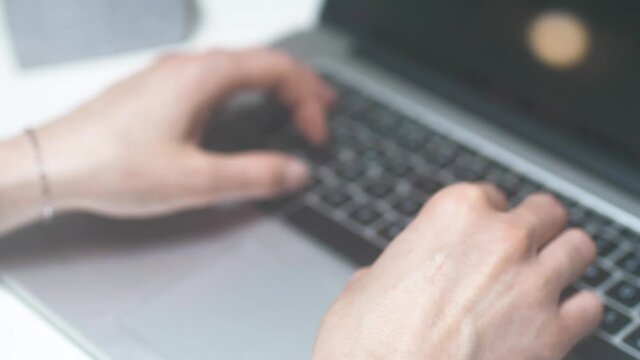 Female tipping on stylish silver colored notebook keyboard in the office. Close up shot with great shallow depth of field. Perfectly suited for topics around the office, IT, Coding, Service and so on.