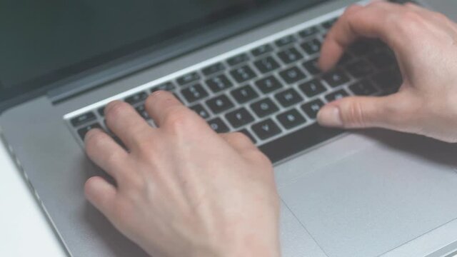 Female tipping on stylish silver colored notebook keyboard close up slomotion. Camera panning to the right. plant on the left side.