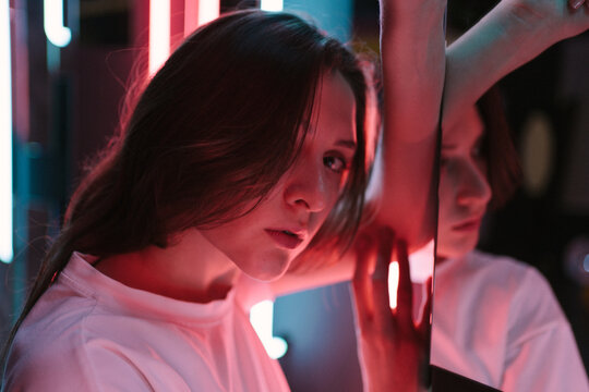 The Colored Bright Pink Lighting On The Face Of A Beautiful Young Woman Is Close-up. Portrait In A Nightclub