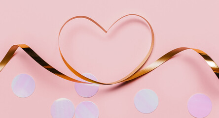 shape heart by gold ribbon on isolated pink background