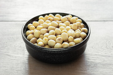 close up of vacuum fried lotus seeds in a ceramic bowl on wooden table. healthy food concept.