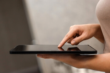 A female hand presses on the screen of a digital tablet close-up, side view. New technology concept, multimedia.