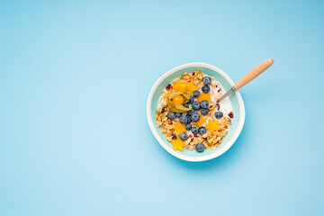 Healthy breakfast. Fresh granola, muesli with milk, honey and berries. Blue color background.Top view