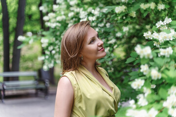 cute caucasian red-haired 30th woman in blooming garden