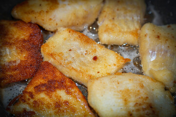 Breaded tender cod fillet pieces are fried in a pan