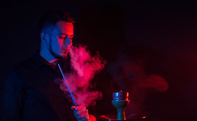 male smoker smokes a hookah in a shisha and lets out a cloud of smoke