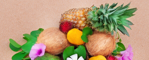 Set of tropical fruits on the sandy beach. Wide photo.