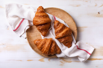 Freshly baked croissants on white wooden table. Morning French continental breakfast with fresh croissants.
